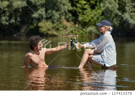 Woman and man on a river with bottle of wine and beer Woman and man on a river with bottle of wine and beer 127413379