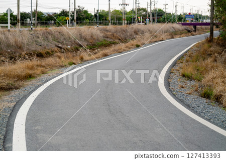 Curving pathway through open fields rural area natural environment perspective journey concept 127413393