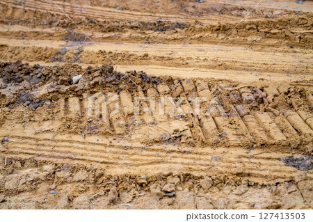 Excavated soil and heavy machinery tracks close-up action at urban construction site 127413503