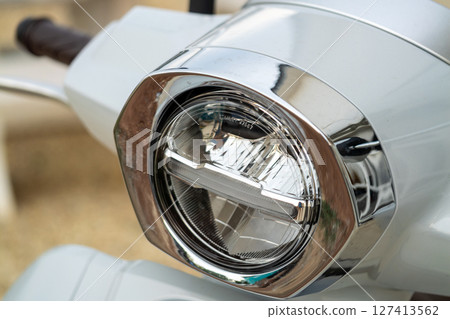 Sleek scooter headlight focus urban setting transport close-up modern aesthetic Sleek scooter headlight focus urban setting transport close-up modern aesthetic 127413562