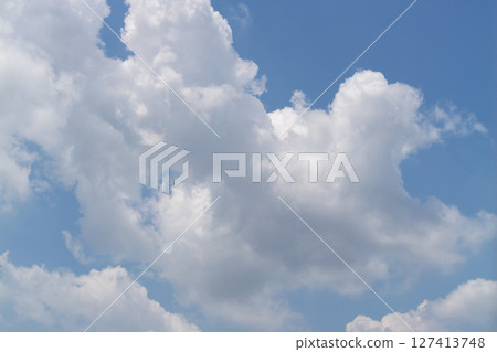 Fluffy white clouds drift calmly across bright blue sky nature scene peaceful atmosphere daytime view 127413748