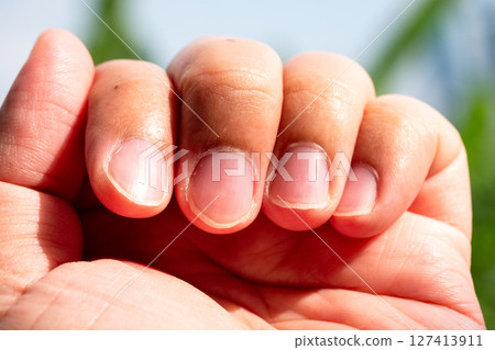 Close-up of human hand with natural nails in bright outdoor setting captured in daylight 127413911