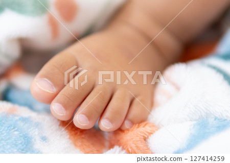 One year old asian girl's tiny foot colorful blanket indoor setting close-up view for baby 127414259