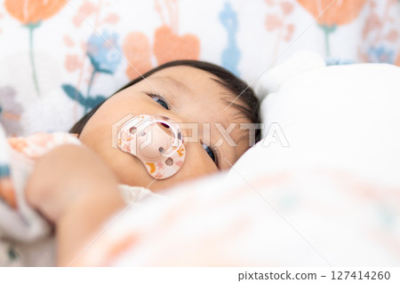 Cuddly baby girl one year old asian indoor nap time in cozy environment close-up view 127414260