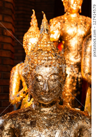 Golden buddha statues display cultural temple art indoor setting close-up perspective Golden buddha statues display cultural temple art indoor setting close-up perspective 127414579