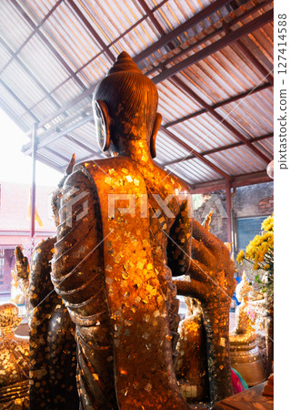 Buddhist ceremony honoring golden statue temple photograph indoor close-up spiritual significance 127414588