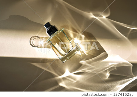 A beautiful perfume bottle on a beige background with beautiful reflected rays. 127416283