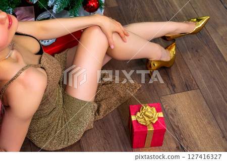 Beautiful young woman sitting on the floor near the christmas tree 127416327
