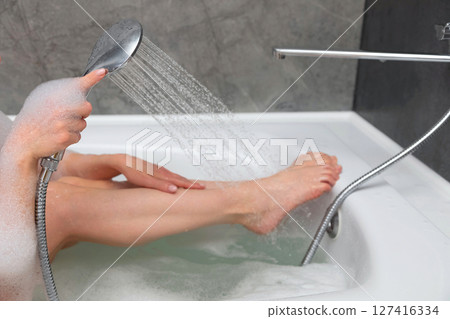 Woman washing her legs in bathroom Woman washing her legs in bathroom 127416334