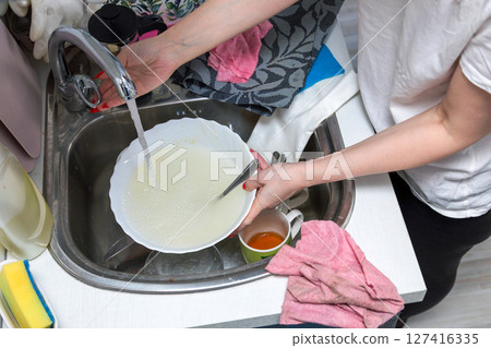 Woman washing dishes in the kitchen. Woman washing dishes in the kitchen. 127416335
