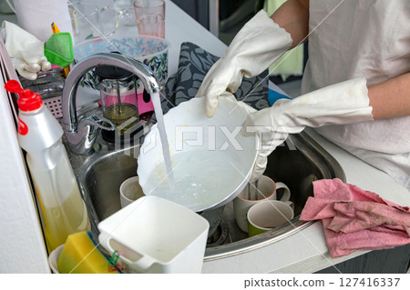Woman washing dishes in the kitchen Woman washing dishes in the kitchen 127416337