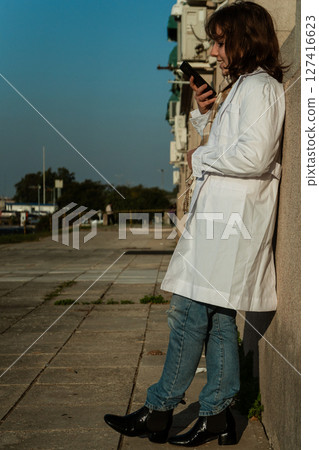Female doctor looking at smartphone during outdoor break 127416623
