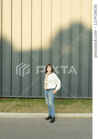 Young woman standing in front of a large gray metal wall Young woman standing in front of a large gray metal wall 127416638