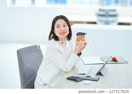 A woman taking a break from work and drinking coffee 127417020