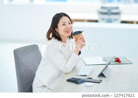 A woman taking a break from work and drinking coffee 127417021