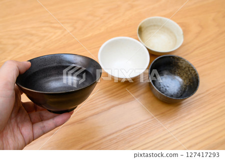 A man's hand choosing a bowl to serve rice in. How to choose tableware 127417293