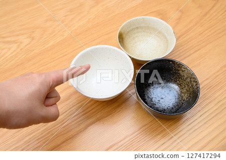 一位男士的手正在挑選盛飯的碗。如何選擇餐具 一位男士的手正在挑選盛飯的碗。如何選擇餐具 127417294