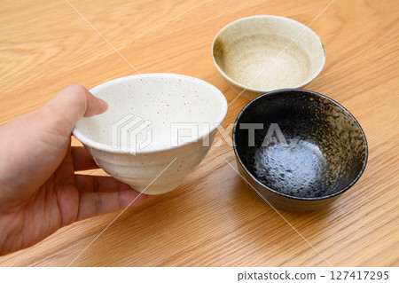 A man's hand choosing a bowl to serve rice in. How to choose tableware A man's hand choosing a bowl to serve rice in. How to choose tableware 127417295
