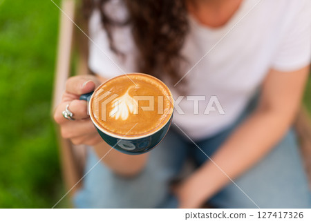 Woman enjoying a cup of coffee outdoors in a peaceful garden setting 127417326