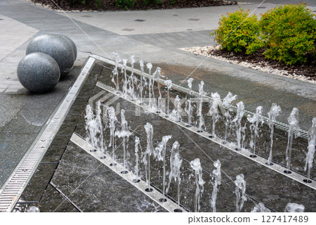 Outdoor decorative fountain with round marble sculptures and flowing water streams. Outdoor decorative fountain with round marble sculptures and flowing water streams. 127417489