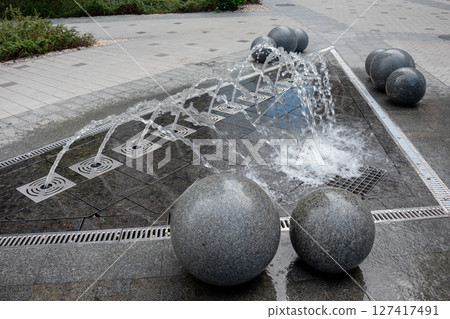 Outdoor decorative fountain with round marble sculptures and flowing water streams. Outdoor decorative fountain with round marble sculptures and flowing water streams. 127417491
