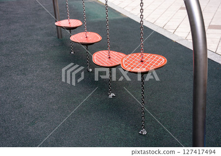 Colorful playground stepping platforms suspended by chains in an urban recreational area 127417494