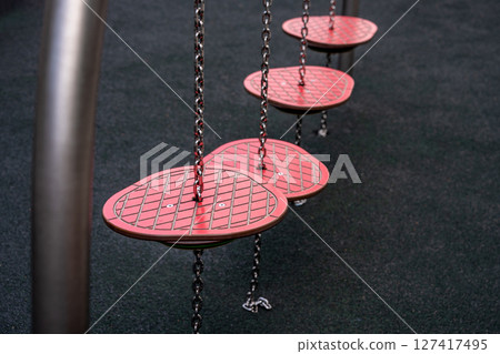 Colorful playground stepping platforms suspended by chains in an urban recreational area 127417495