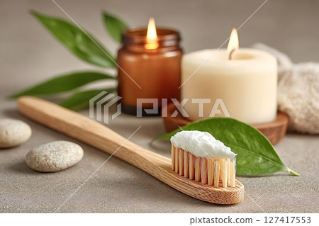 Bamboo toothbrush with toothpaste, candles and green leaves promoting oral hygiene 127417553