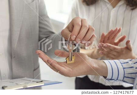 Professional realtor agent giving house key to man customer standing in office Professional realtor agent giving house key to man customer standing in office 127417677