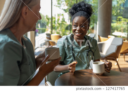 Two female doctors having coffee and discussing something Two female doctors having coffee and discussing something 127417765