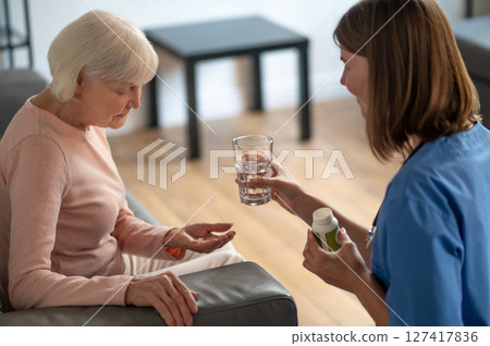 Care assistant giving medicine to an elderly woman 127417836