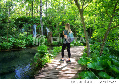 Young woman with backpack on wooden path in Plitvice Lakes 127417927