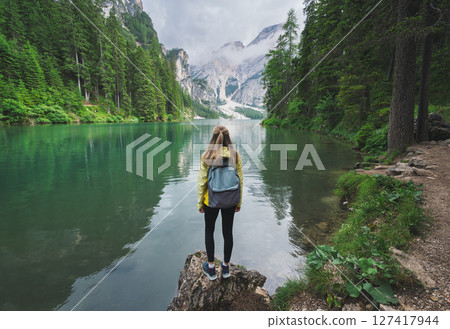 Young woman with backpack on the stone on mountain lake Braies Young woman with backpack on the stone on mountain lake Braies 127417944