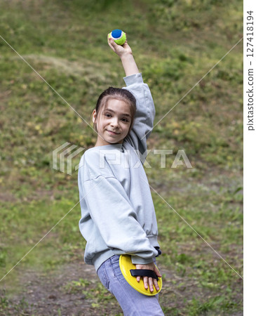 Young girl playing with a foam ball and racket outdoors in a park Young girl playing with a foam ball and racket outdoors in a park 127418194