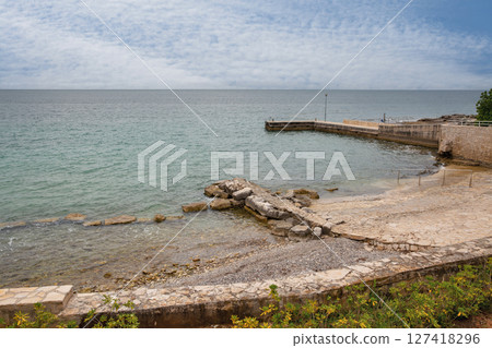 Stone pier and rocky beach on calm sea coast, Croatia. 127418296