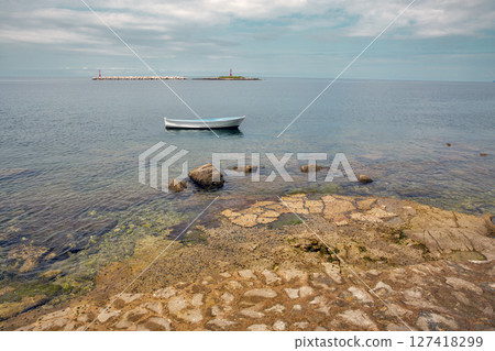 Small white boat, calm sea, rocky shore, lighthouse. Porec, Croatia. Small white boat, calm sea, rocky shore, lighthouse. Porec, Croatia. 127418299