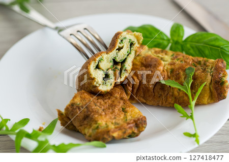 Delicious homemade omelette in the form of a roll with greens on a wooden table Delicious homemade omelette in the form of a roll with greens on a wooden table 127418477