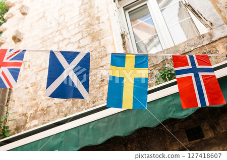 Nordic and British flags strung across a charming European street. Cultural celebration, travel atmosphere, and European unity in a historic stone courtyard. 127418607