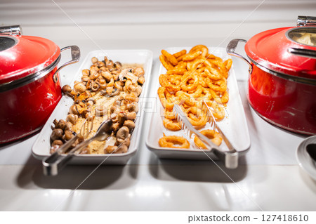Variety of hot breakfast dishes on buffet table in hotel dining area. Morning meal options, protein-rich food, and colorful nutrition concept. 127418610