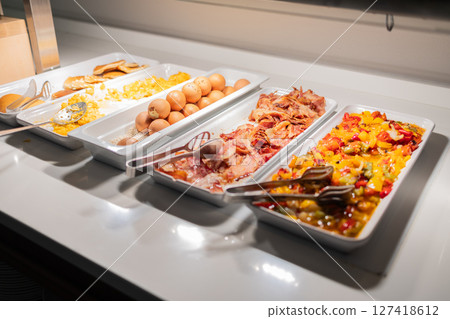 Variety of hot breakfast dishes on buffet table in hotel dining area. Morning meal options, protein-rich food, and colorful nutrition concept. Variety of hot breakfast dishes on buffet table in hotel dining area. Morning meal options, protein-rich food, and colorful nutrition concept. 127418612