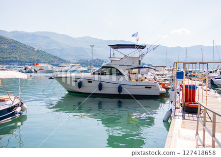 Luxury motor yacht docked at marina. Coastal lifestyle, leisure boating, and maritime tourism in summer harbor scene. Luxury motor yacht docked at marina. Coastal lifestyle, leisure boating, and maritime tourism in summer harbor scene. 127418658