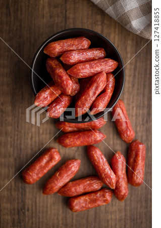 Mini salami sausages in bowl on wooden table. Top view. Mini salami sausages in bowl on wooden table. Top view. 127418855