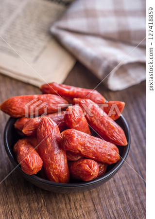 Mini salami sausages in bowl on wooden table. Mini salami sausages in bowl on wooden table. 127418859