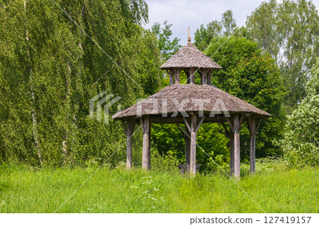 A charming empty wooden gazebo surrounded by vibrant greenery A charming empty wooden gazebo surrounded by vibrant greenery 127419157