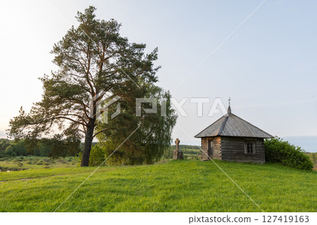 A picturesque ancient wooden chapel surrounded by lush greenery 127419163