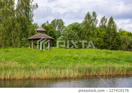 An empty vintage wooden gazebo surrounded by vibrant greenery An empty vintage wooden gazebo surrounded by vibrant greenery 127419176