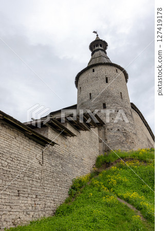 Pskov Kremlin exterior. Medieval stone tower stands against a cloudy sky Pskov Kremlin exterior. Medieval stone tower stands against a cloudy sky 127419178