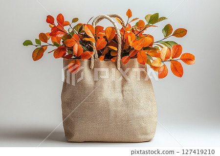 Reusable shopping bag made of fabric with a branches with yellow leaves on a white background. Reusable shopping bag made of fabric with a branches with yellow leaves on a white background. 127419210