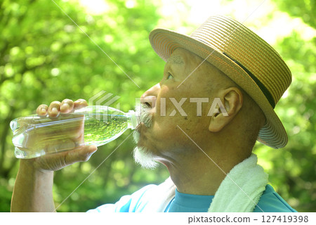 An old man hydrating in a mountain stream 127419398