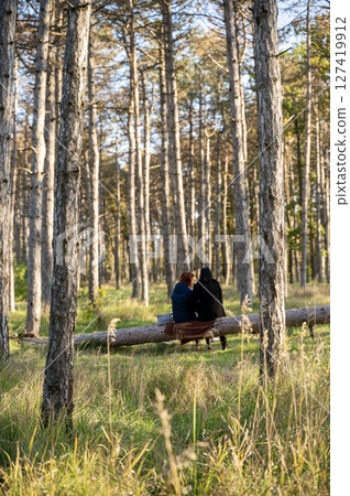 A person sitting on a bench next to a forest 127419912